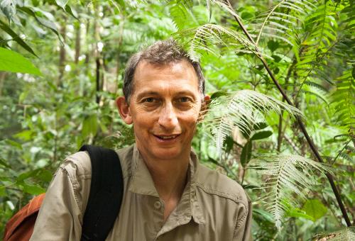 A close up portrait of Jonathan Drori surrounded by green plants